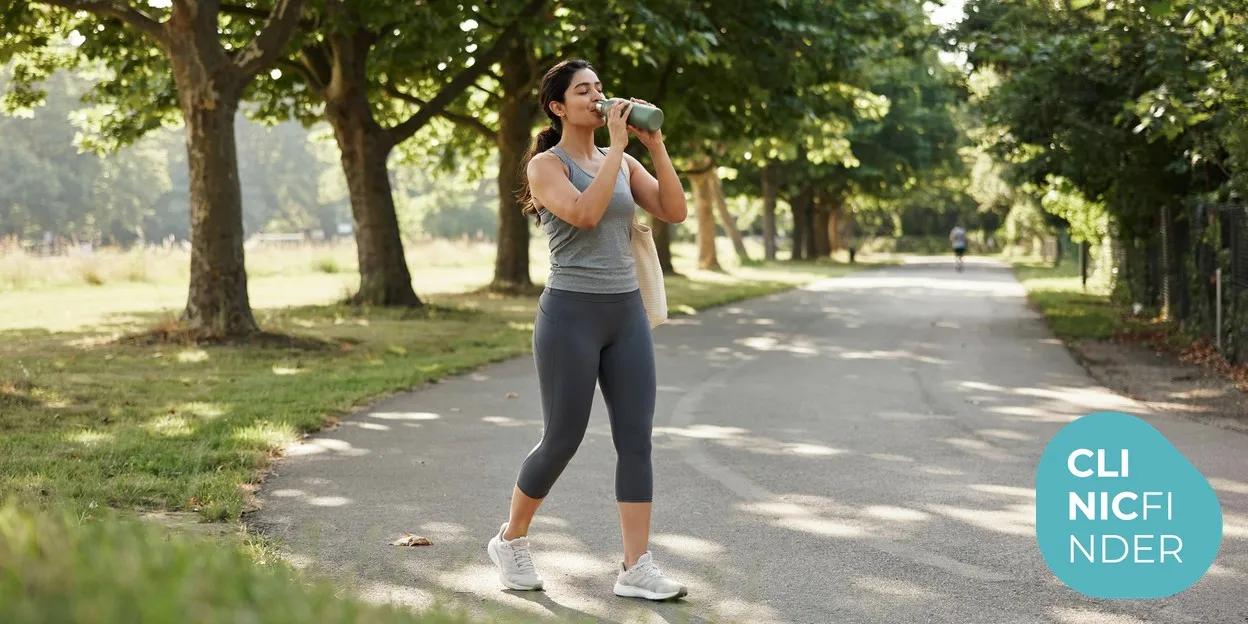 A woman drinking water from a bottle outdoors after a brisk walk, reflecting the hydration and healthy habits that support body-contouring results