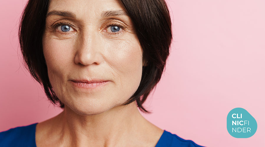 Midlife woman looking at the camera against a pink background